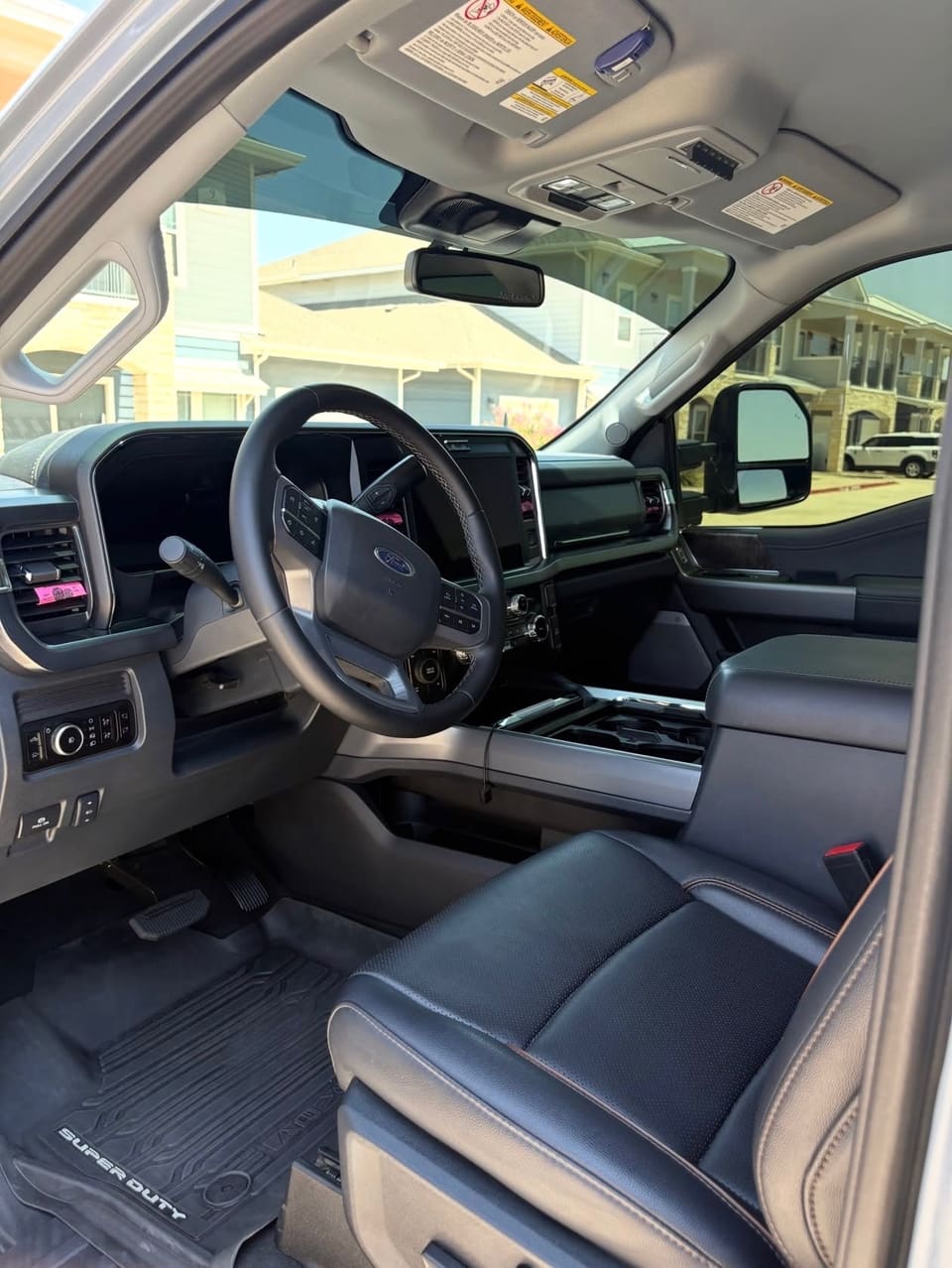 A truck cab interior after detailing: clean dashboard and console, vacuumed Super Duty floor mats and clear glass.